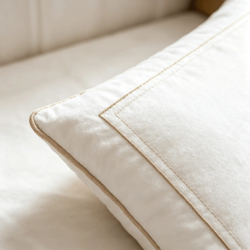 Close-up of a white bed pillow corner with tan piped edge